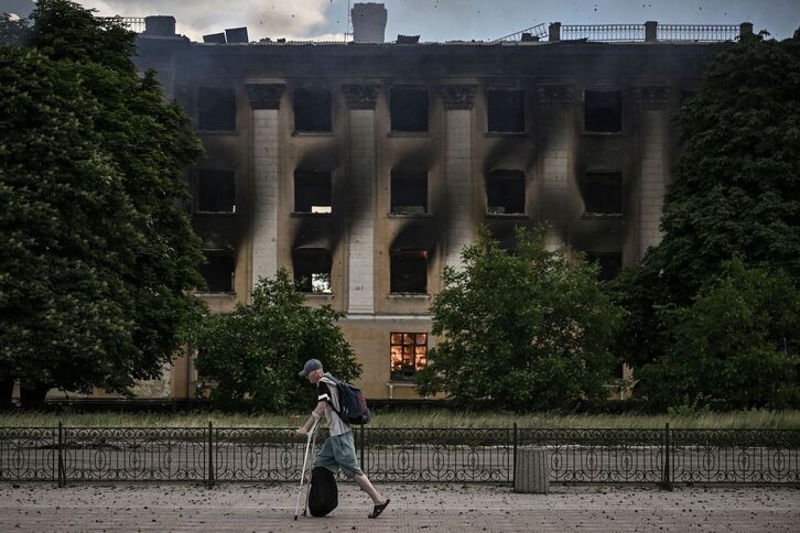 Un hombre camina junto a un edificio en llamas en la región del Donbas. 