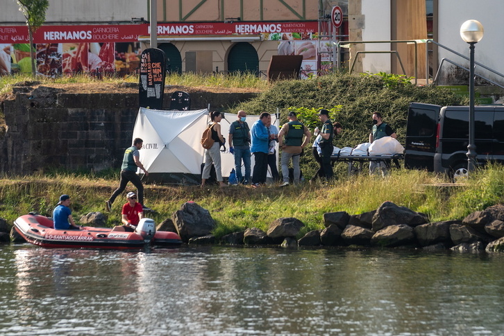 El cadáver del migrante es introducido en un coche fúnebre tras ser rescatado a la orilla del Bidasoa.