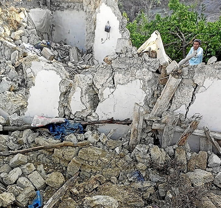 Un hombre, junto a una vivienda destruida en el distrito de Gayan.