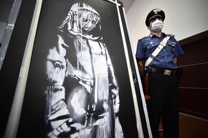 Foto tomada el 11 de junio de 2020: un carabinero custodia una obra de arte atribuida a Banksy que fue robada en el Bataclan de París en 2019 y localizada en Italia.