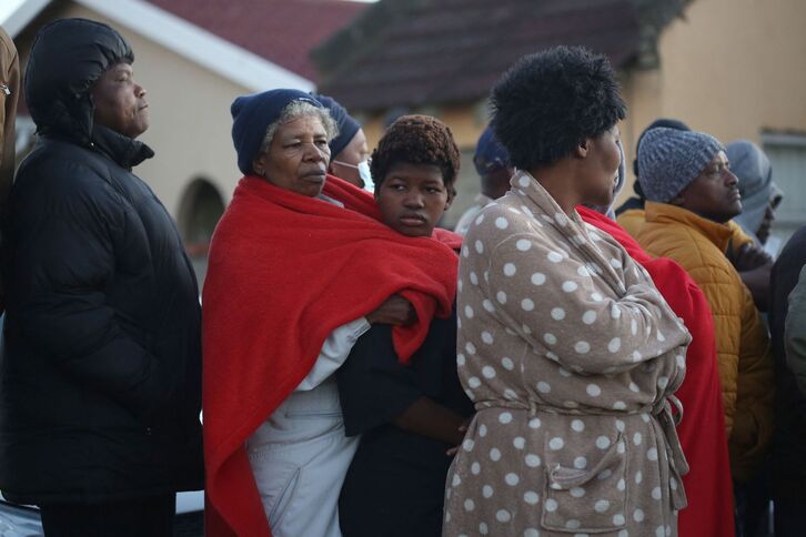 Familiares y miembros de la comunidad esperando noticias en las proximidades del lugar donde se hallaron los cuerpos de los jóvenes, en la ciudad de East London, el domingo.