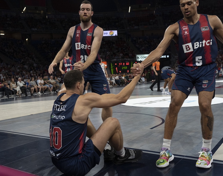 Wetzell, en el suelo, es ayudado a levantar por Costello y Baldwin. 