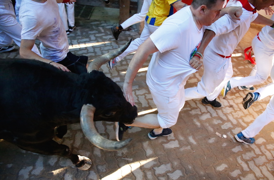 Un mozo accede al callejón rozando la cabeza de uno de los toros.