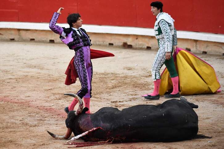 Corrida de toros en estos Sanfermines: un toro agoniza en el suelo mientras que el torero Andrés Roca lo celebra. 