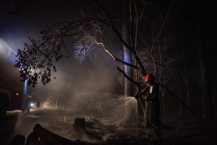 Un bombero riega una zona calcinada en las Landas.