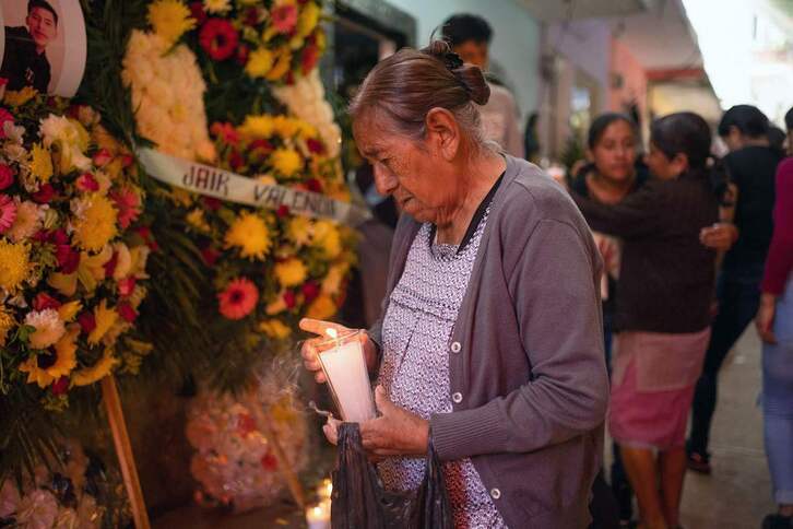 Una mujer enciende una vela en el funeral conjunto de Jair, Yovani y Misael, tres primos que fallecieron en el remolque. 