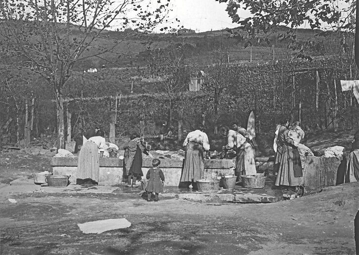 Emakume talde bat ibaian arropa garbitzen.