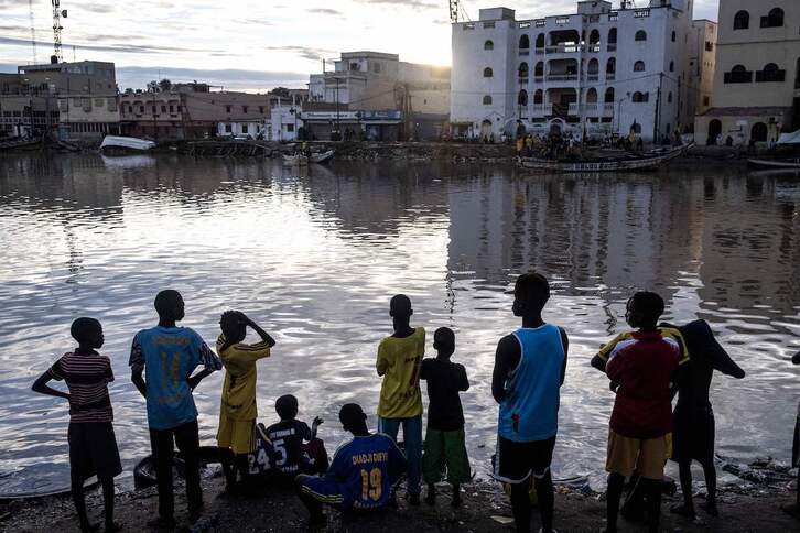 Dozena bat ume arrantzaleen txalupei begira Guet Ndarren, Senegalen.