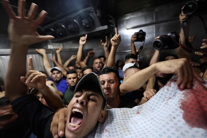 Un grupo de palestinos, en el momento en que se llevan el cuerpo de una de las víctimas del bombardeo israelí sobre Gaza. 