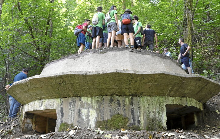 Ezker-eskuin, gazteak Etxalarko Lizarrieta mendian berreskuratu duten metrailadore-habian, Ana Anton Alacanteko boluntarioa, eta dantzarien aurreskua Berako Argaitza harrobian.