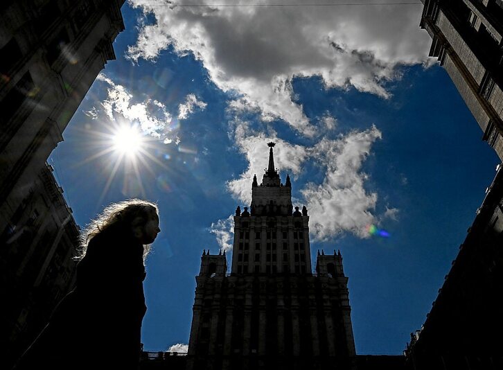 Stalinen garaiko eraikin erraldoi baten azpitik emakume bat pasiatzen.  Kirill KUDRYAVTSEV I AFP