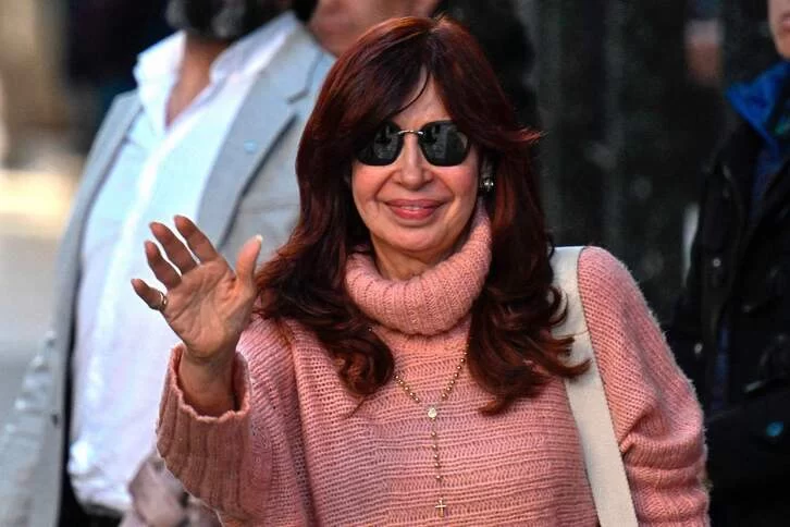 Cristina Fernández saluda a los congregados a las puertas de su casa en la primera vez que sale desde que ocurrió el ataque. (Luis ROBAYO | AFP)