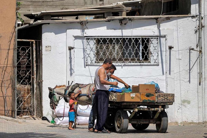 Un hombre compra a un vendedor callejero con un carro tirado por un burro en el campo de refugiados de Jabalia, al norte de Gaza.