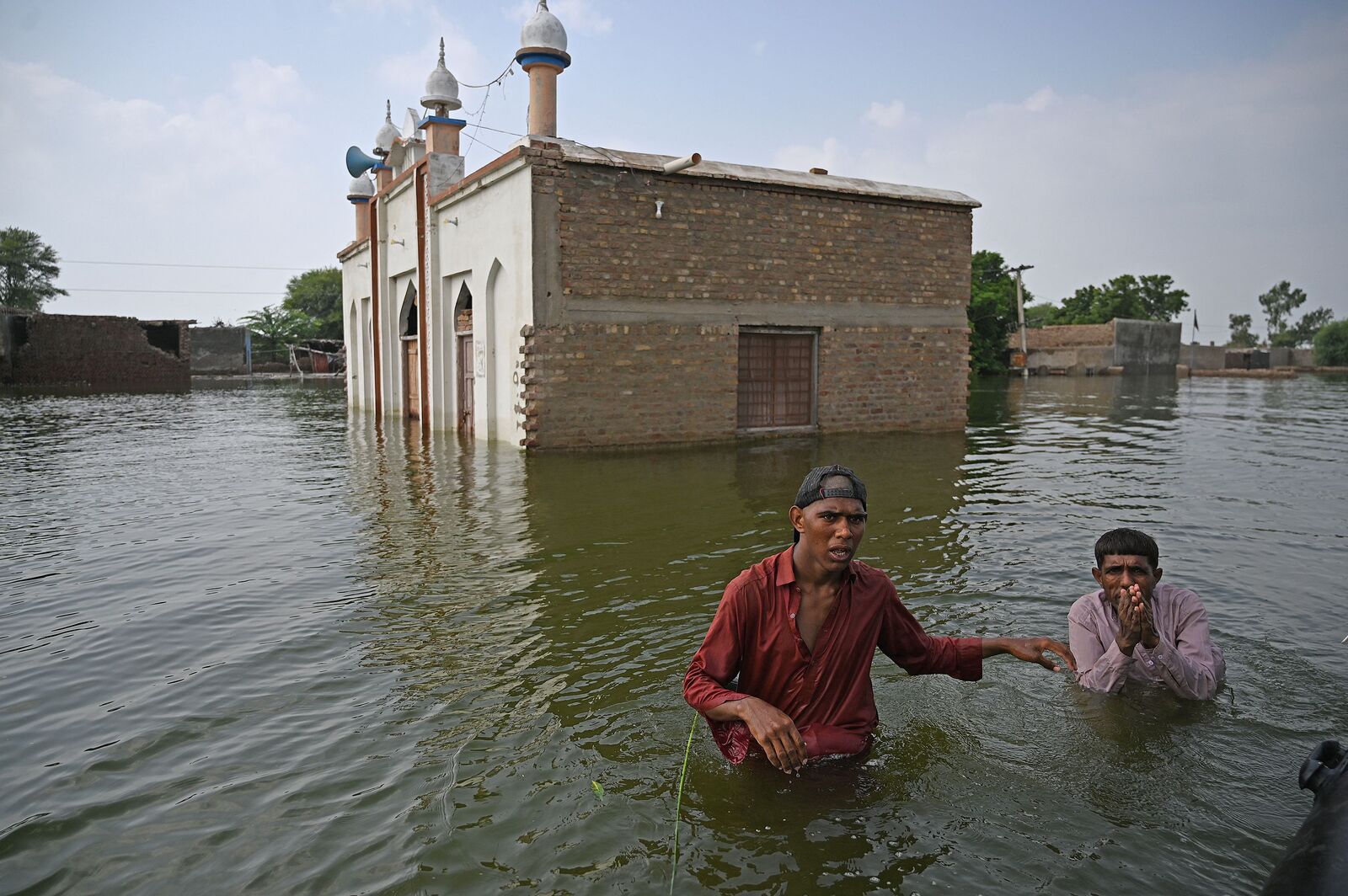Dos hombres caminan con el agua a la cintura. (Aamir QURESHI / AFP)