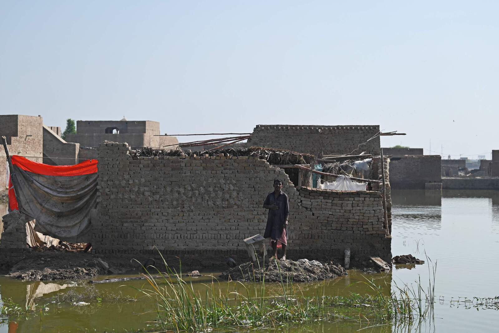 Un hombre espera ayuda junto a un edificio en ruinas. (Aamir QURESHI / AFP) 