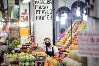  Una mujer en un puesto de frutas en un mercado en México.