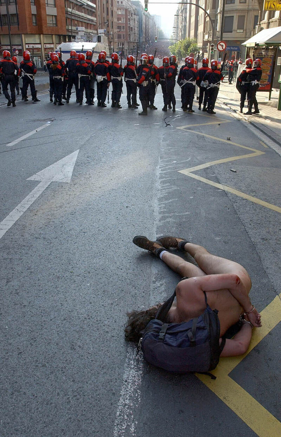 Un manifestante que se desnudó en señal de protesta, en el suelo y esposado tras la carga.