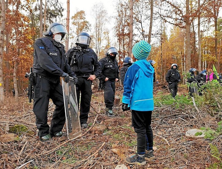 Haur bat poliziari aurre egiten baso batean.
