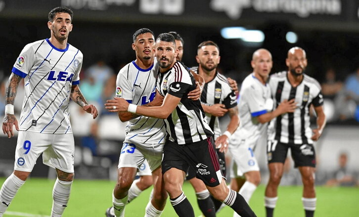 Jugadores de los dos equipos toman posiciones en el área.