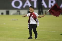 Un chaval ondea la bandera del emirato al final de un entrenamiento de la selección qatarí.