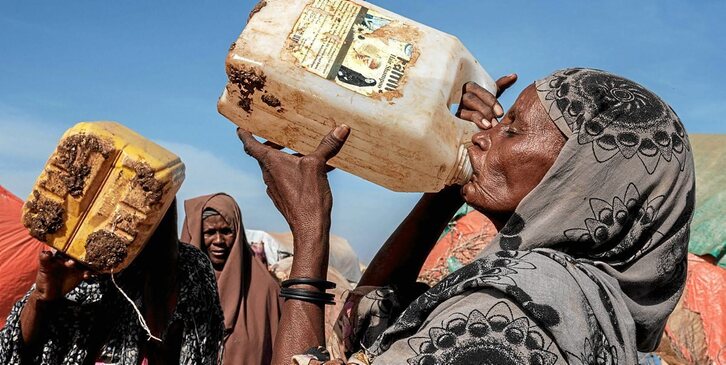 Emakume bat bidoi batetik ura edaten, Somaliako Muuri desplazatuen eremuan. (Mohamed ISACK/AFP)