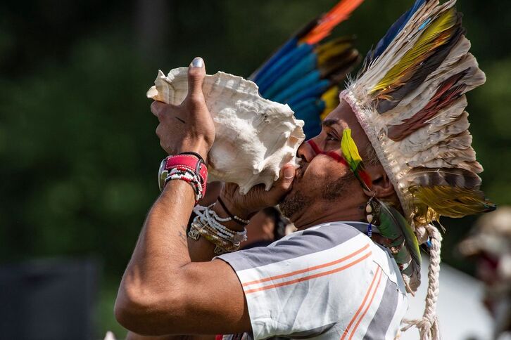 Un indígena sopla una caracola durante la oración de los cuatro vientos en el Día de los Pueblos Originarios en Newton, Massachusetts.