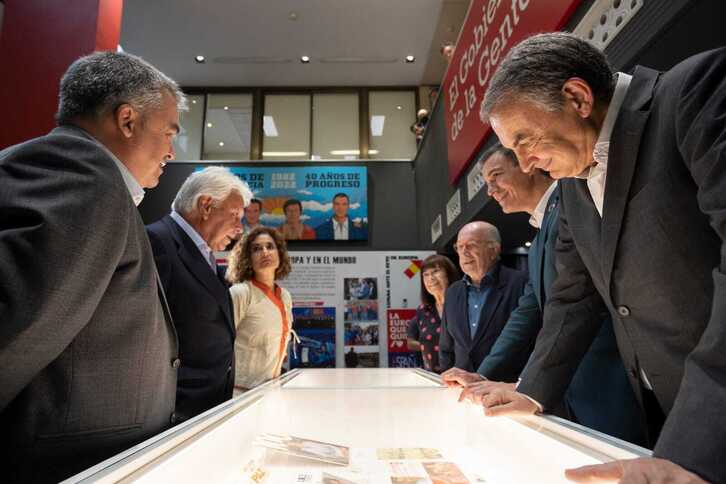 Felipe González y Pedro Sánchez se miran mientras José Luis Rodríguez Zapatero observa la exposición en Ferraz. 