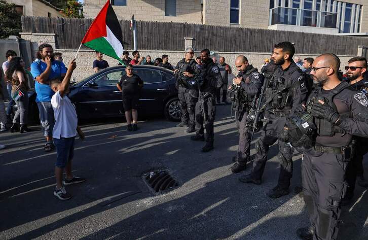 Un niño ondea una bandera palestina en Jerusalén, frente a la Policía israelí.