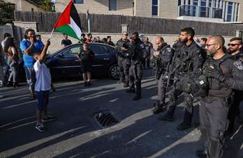 Un niño ondea una bandera palestina en Jerusalén, frente a la Policía israelí.