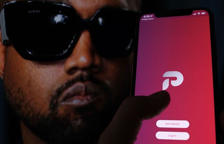 Un usuario accede a la aplicación Parler frente a una imágen de Kanye West. 