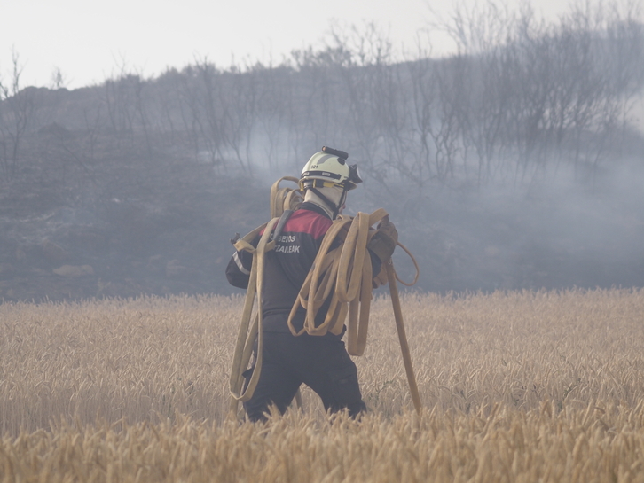Un bombero acarrea metros de manguera durante la oleada de incendios de junio. 