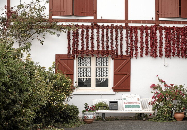 Traído a Europa por los conquistadores del continente americano, encontramos vestigios de la cultura del pimiento en Ipar Euskal Herria desde 1650. Bajo estas líneas, tiras expuestas en la fachada de una vivienda de Ezpeleta.