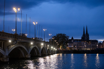 La noche cae en la capital labortana en esta vista hacia su Ayuntamiento desde el puente de Saint-Esprit..