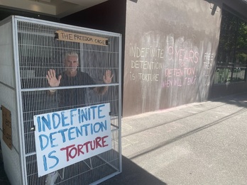 Craig Foster dentro de una jaula para denunciar la detención indefinida.