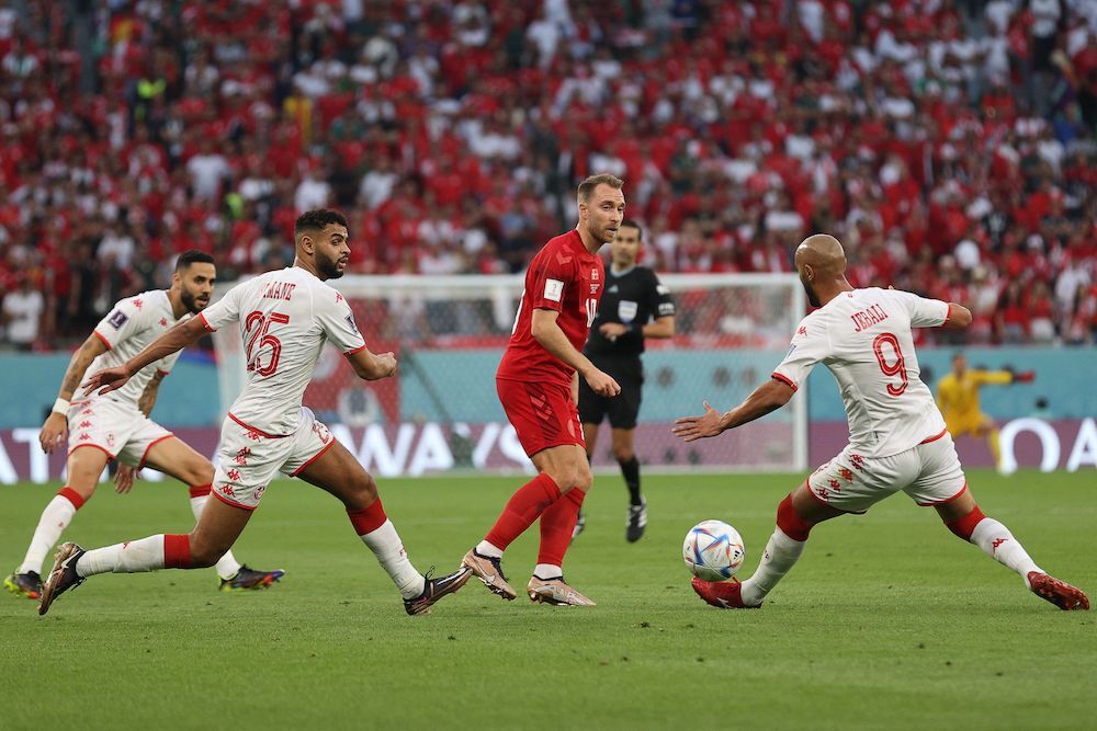 Eriksen es perseguido por varios jugadores tunecinos. (Adrian DENNIS / AFP)