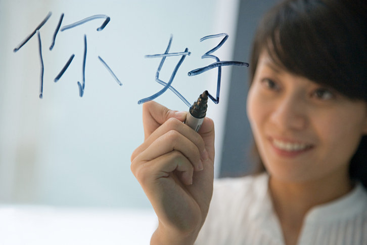 Una mujer escribe un saludo en chino. 