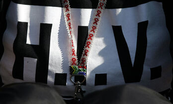 Un collar con la bandera sudafricana y las siglas del VIH.
