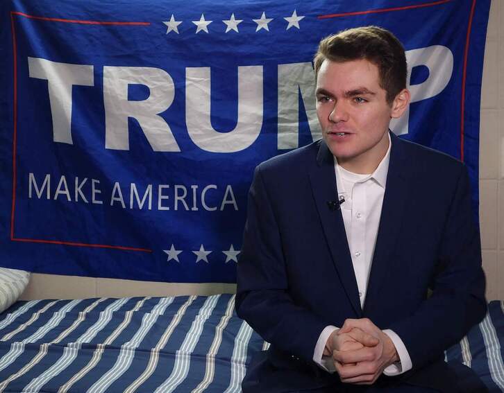 El supremacista blanco Nick Fuentes delante de una bandera con el eslogan de Donald Trump.