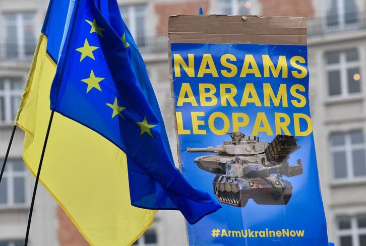 Banderas y carteles que reclaman más armamento en una manifestación ante la reunión de ministros en Bruselas.