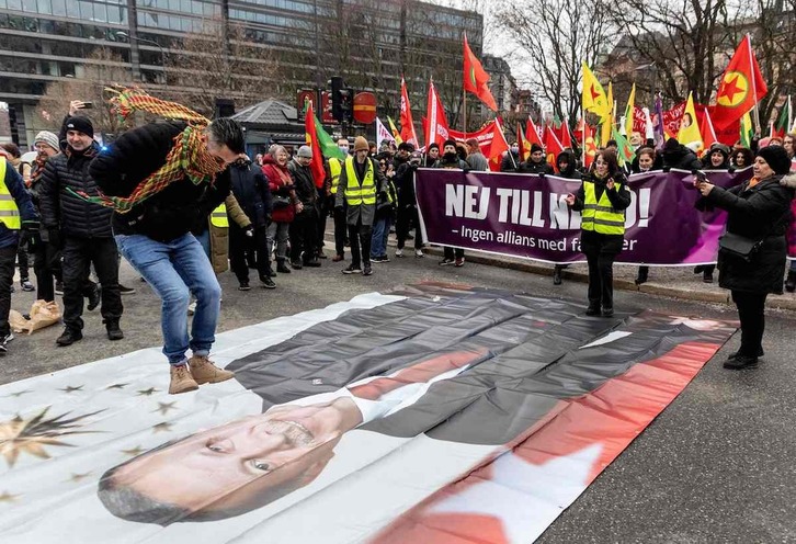 Un manifestante kurdo salta sobre un retrato de Erdogan en una protesta en Estocolmo.
