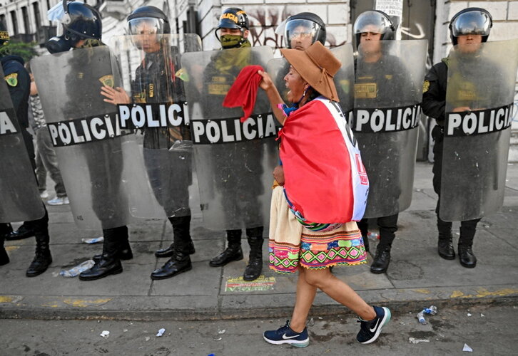 Una manifestante indígena corea consignas mientras camina ante un cordón policial.