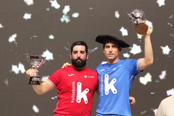 Ibai Perez, gorriz, eta Dan Necol, txapelarekin, Bizkaia pilotalekuko podiumean.