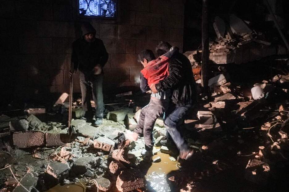 Un hombre se lleva a un niño herido luego de un terremoto en la ciudad de Jandaris.