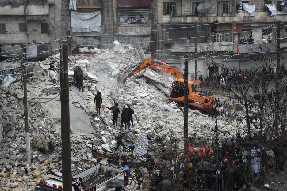 La gente observa cómo los equipos de rescate buscan sobrevivientes bajo los escombros de un edificio derrumbado en Alepo.