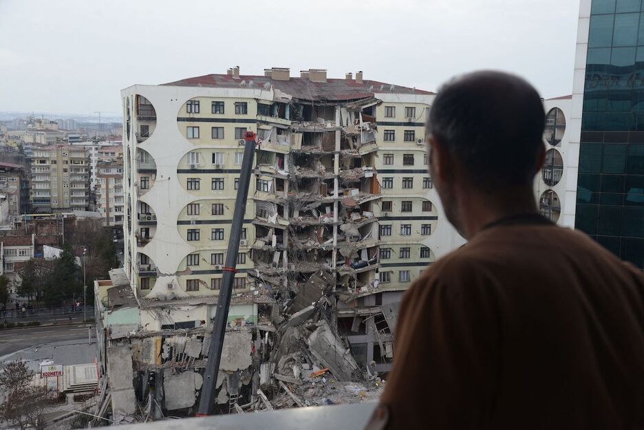 Un hombre mira desde la ventana un edificio derrumbado en la ciudad de Diyarbakir.