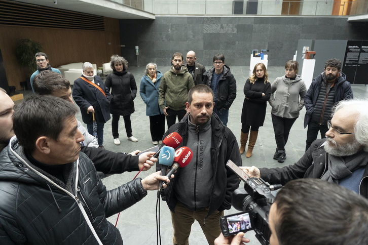 Nafarroako Torturatuen Sareko kide Jorge Txokarro Parlamentuan kazetariei adierazpenak egiten, atzean beste kide eta sindikatu nagusietako ordekariak dituela.