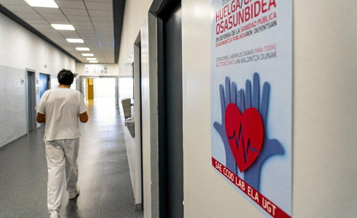 Uno de los pasillos del hospital con un cartel llamando al paro del día 15.