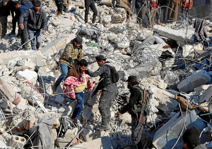 Un hombre lleva el cuerpo de un niño sacado de entre las ruinas de una casa en Harim, provincia siria de Idleb.