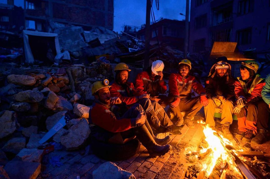Rescatadores descansan alrededor de una hoguera en Hatay, Turquía.