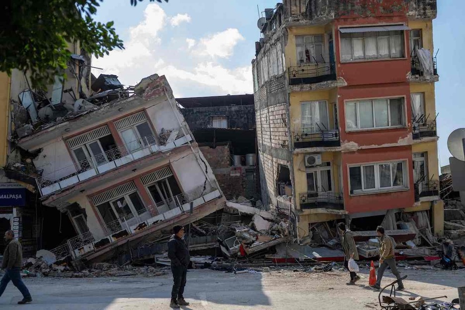 La gente camina junto a los edificios dañados en la ciudad histórica de Antakya en Hatay.
